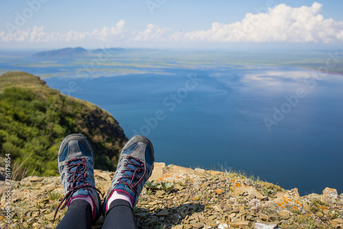 tourist legs in trekking shoes, sea view from a cliff