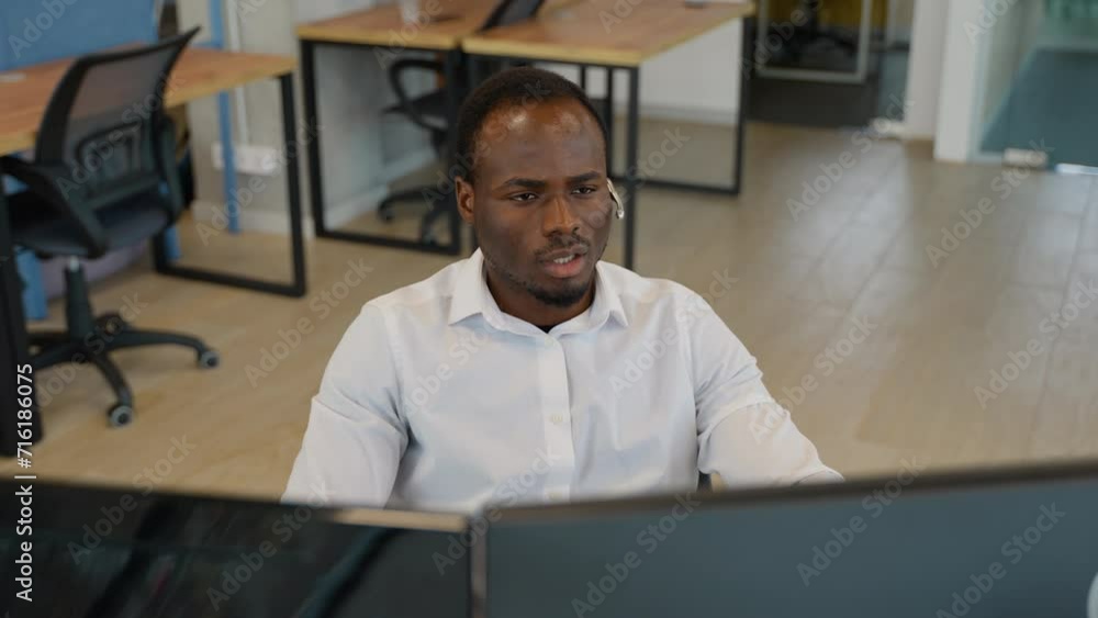 Black trader or businessman in formal wear working with charts and market reports on computer screens in his modern office Black trader or businessman in formal wear working with charts and market reports on computer screens in his modern office