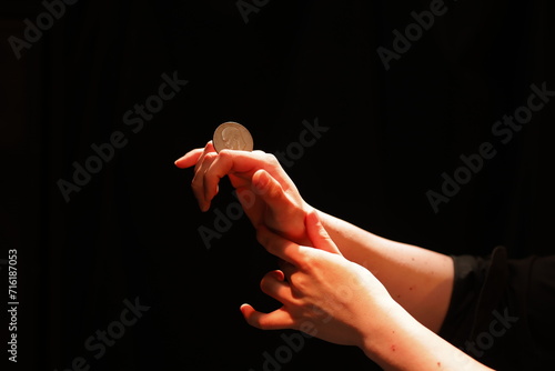 マジシャンがコインを持っている手元画像 Image of the magician holding a coin in his hand photo