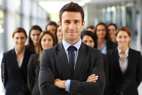Professional man in suit standing confidently in front of group of business people. This image can be used to depict leadership, teamwork, or business meetings