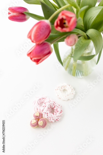 Fototapeta Naklejka Na Ścianę i Meble -  Pink tulips and heart-shaped pastries and candies on a white canvas close-up. Background for Valentine's Day, Easter. Gift for Women's Day, March 8th. Mockup