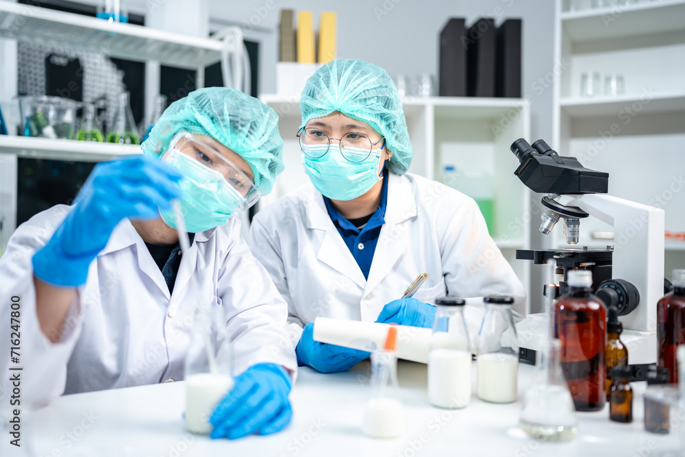 A Scientists or nutritionists are working on a sample of milk in biotechnology laboratory, genetic and bacteria research, dairy product quality control, protein, glucose and lactose percentage test. A Scientists or nutritionists are working on a sample of milk in biotechnology laboratory, genetic and bacteria research, dairy product quality control, protein, glucose and lactose percentage test.