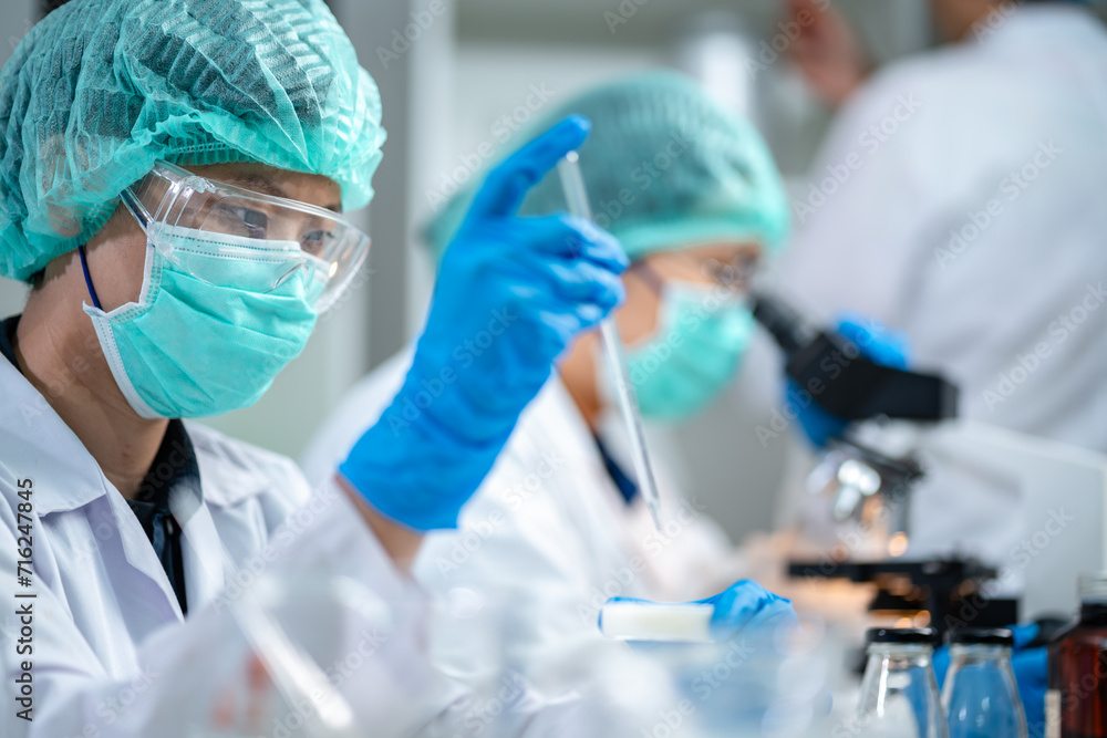 A Scientists or nutritionists are working on a sample of milk in biotechnology laboratory, genetic and bacteria research, dairy product quality control, protein, glucose and lactose percentage test. A Scientists or nutritionists are working on a sample of milk in biotechnology laboratory, genetic and bacteria research, dairy product quality control, protein, glucose and lactose percentage test.