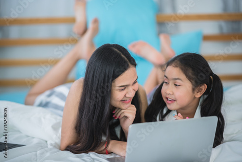 Mother and daughter are enjoy spending time using laptop watching or learning together, relationship bonding or connection between parents, technology and cyberspace lifestyle, online education class.