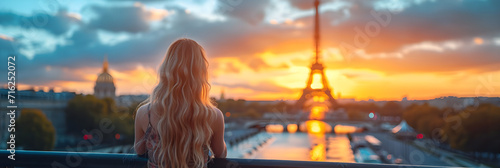 A beautiful slim chic girl with long blonde hair stands in front of the Eiffel Tower in Paris, France.