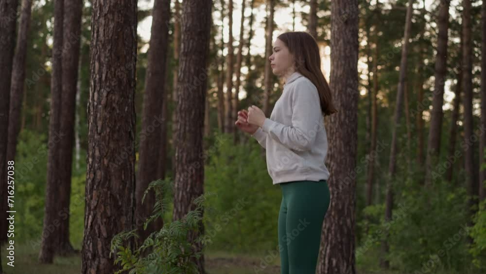 Woman jumps exercising in forest with trees. Athlete warms up before active jog at sunset. Productive fitness activities and improved endurance Woman jumps exercising in forest with trees. Athlete warms up before active jog at sunset. Productive fitness activities and improved endurance