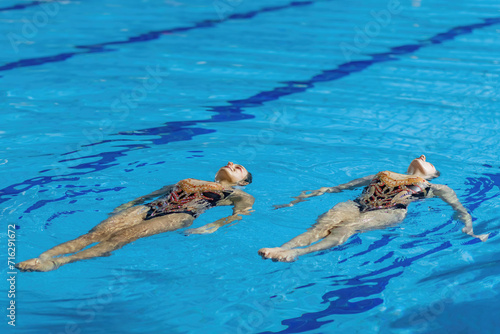 The elegance of a synchronized swimming female duet during their dedicated training session, mastering intricate moves with fluidity and precision