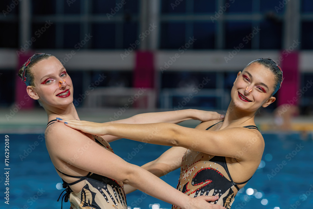 Synchronized swimming duet by the poolside, poised and graceful, prepares for a captivating performance.