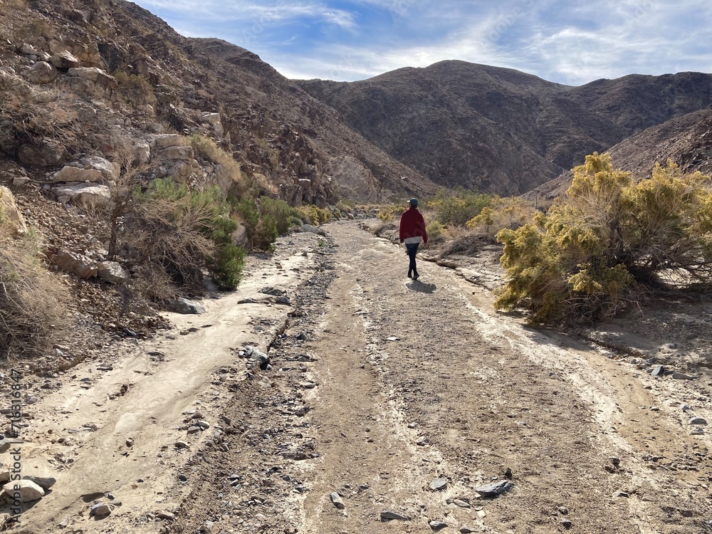 Lone hiker. going down dirt trail between mountains