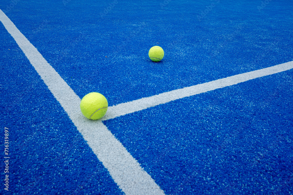 two paddle tennis balls over the line of a paddle tennis court
