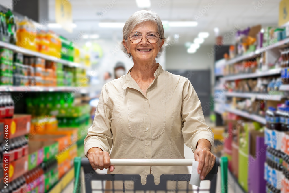 Caucasian elderly woman  while purchasing household products in supermarket. Senior female with shopping cart in departement store