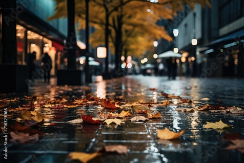 Wet autumn leaves on the ground of a vibrant city street at night.