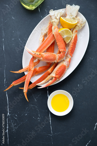 Plate with boiled opilio or snow crab on a black marble background, vertical shot, view from above