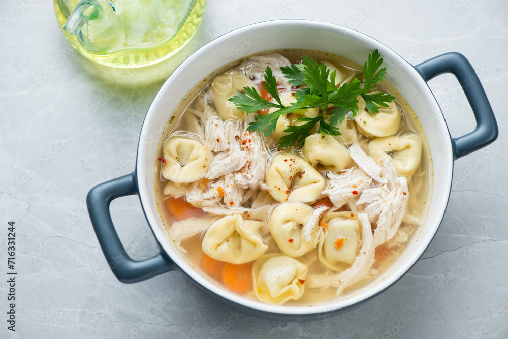Serving pan with tortellini and chicken soup on a light-grey granite background, horizontal shot Serving pan with tortellini and chicken soup on a light-grey granite background, horizontal shot