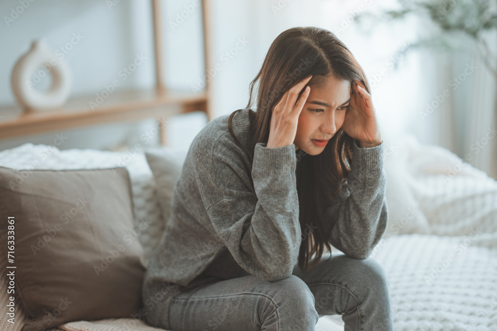 Depressed young woman sitting on couch in the living room at home, Frustrated confused female feels unhappy problem in personal life quarrel break up with boyfriend - obrazy, fototapety, plakaty 