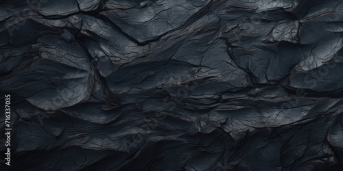 Close-up shot of a rugged black rock surface, showcasing intricate textures and shadows.