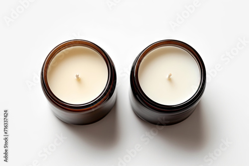  two unused white hand-poured soy wax scented candles in brown glass jars on white background