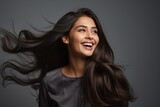 Energetic smiling young female of Indian ethnicity having long flowing hair