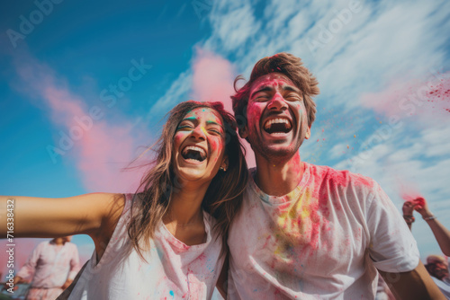 Young couple of Indian ethnicity celebrating Holi festival with colours against a blue sky background