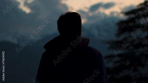 Silhouette shot of an Indian man staring at the snow covered mountains during the sunset at Manali in Himachal Pradesh, India. Man staring at the beautiful mountain peaks during sunset.