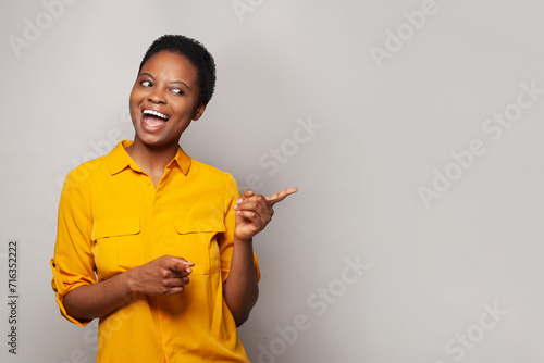 Smiling woman pointing finger at light gray studio wall banner background