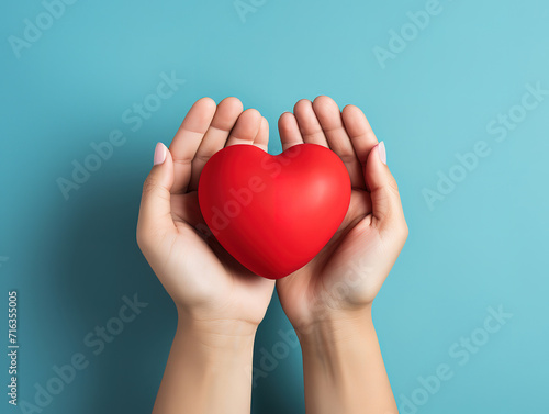 Family holding small red heart in hands on color background
