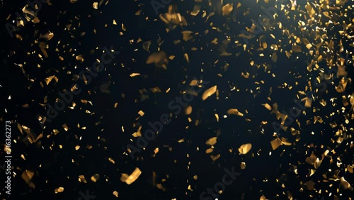 Golden confetti scattered against a black background. The light pieces of paper glitter as they dance in the darkness.
 photo