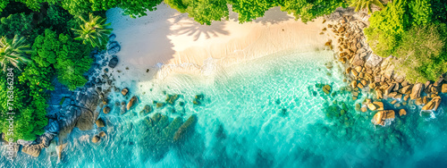  Aerial view of a tropical paradise with clear turquoise waters, white sandy beach, and lush greenery.