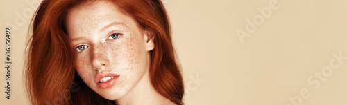 Fotografia A close-up portrait of a young woman with striking red hair and a complexion dotted with freckles, her blue eyes gaze away thoughtfully