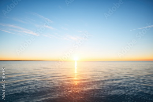 sunrise over calm ocean with clear blue sky