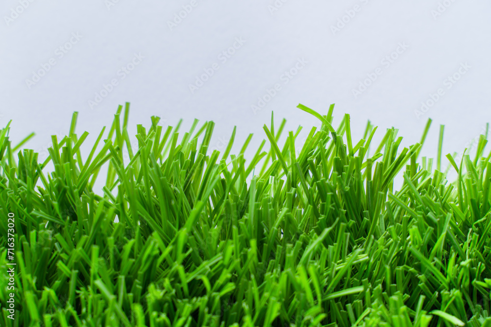 Obraz premium Close up of vibrant green artificial grass turf in residential. white background.