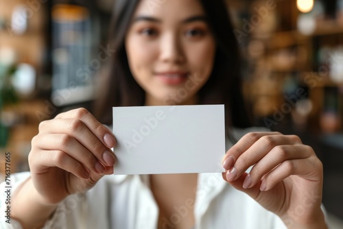 Young Woman Holding a Blank White Card in Front of Her Face Indoors During Daytime