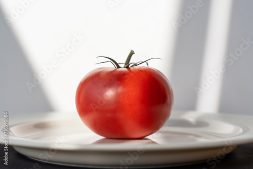 closeup tomato on white plate, shadow on white background. High quality photo
