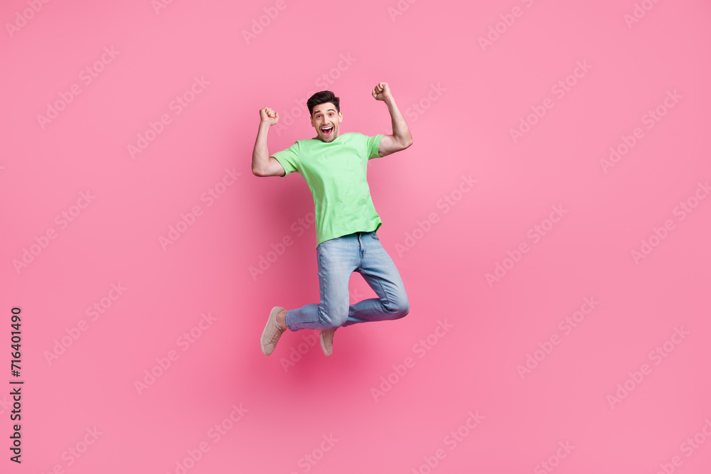 Full length photo of sportsman jumping trampoline wear green t shirt enjoying his football team victory isolated on pink color background