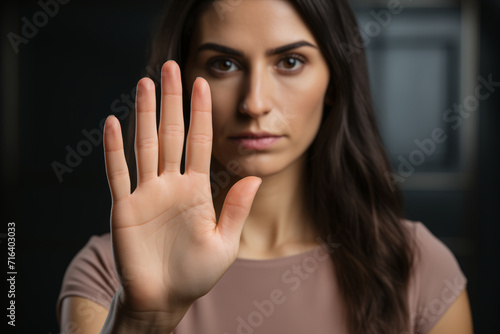 Portrait of a serious young hispanic woman standing with outstretched hand showing stop gesture, domestic violence concept. Stop violence and abuse.