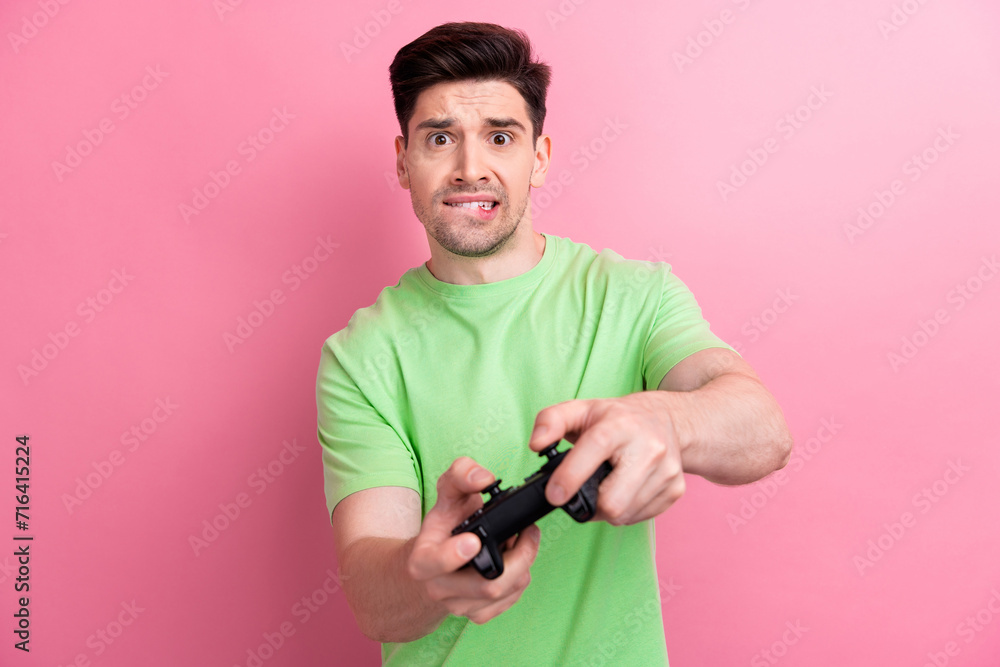 Portrait of stressed young man have fun free time gamer bite lips nervous competition cant complete level isolated on pink color background - obrazy, fototapety, plakaty 