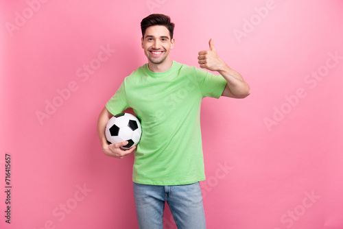 Photo of young amateur cheerful sportsman enjoying betting company holding soccer ball thumb up rate isolated on pink color background © deagreez