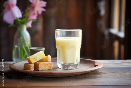 glass of buttermilk on rustic wood with fresh butter cubes