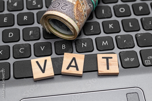 Napis VAT obok polskich pieniędzy na klawiaturze laptopa, podatek od towarów i usług 