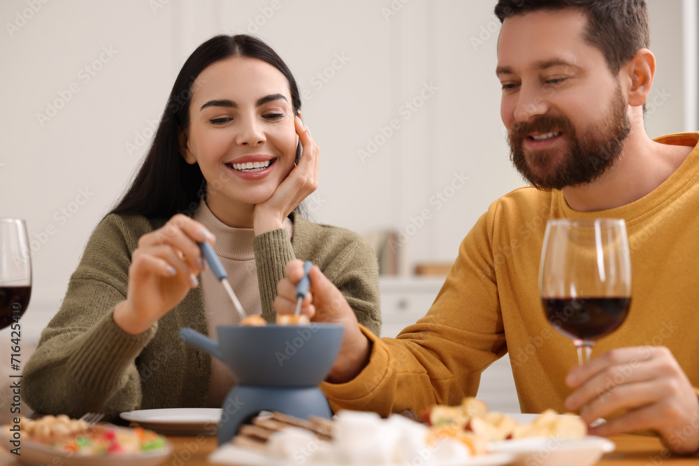 Affectionate couple enjoying fondue during romantic date at home Affectionate couple enjoying fondue during romantic date at home