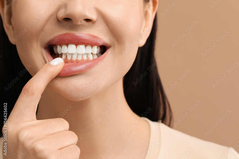 Obraz premium Woman showing her clean teeth on beige background, closeup