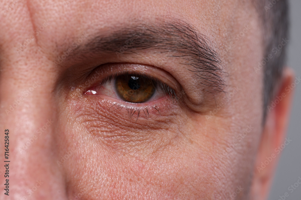 Closeup view of man with beautiful eyes on grey background Closeup view of man with beautiful eyes on grey background