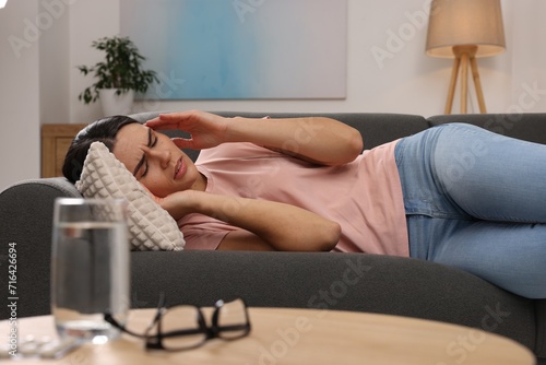 Sad woman suffering from headache on sofa indoors photo