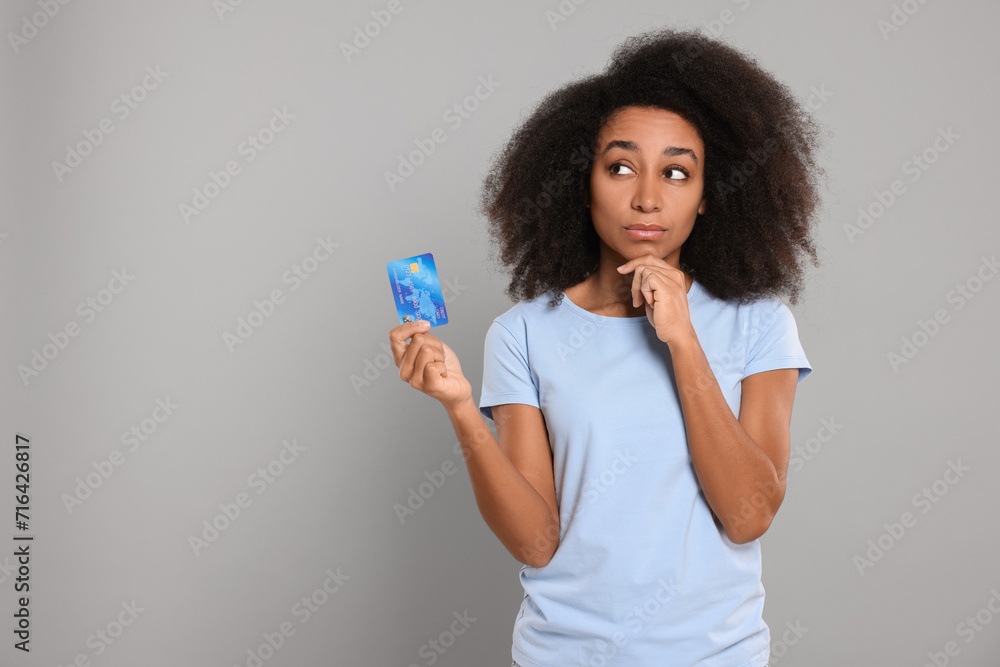 Woman with credit card on grey background, space for text. Debt problem Woman with credit card on grey background, space for text. Debt problem