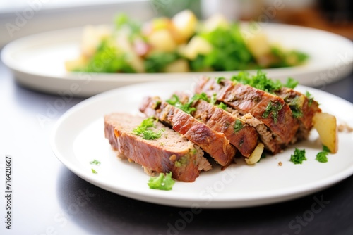 sliced meatloaf on white plate with parsley garnish