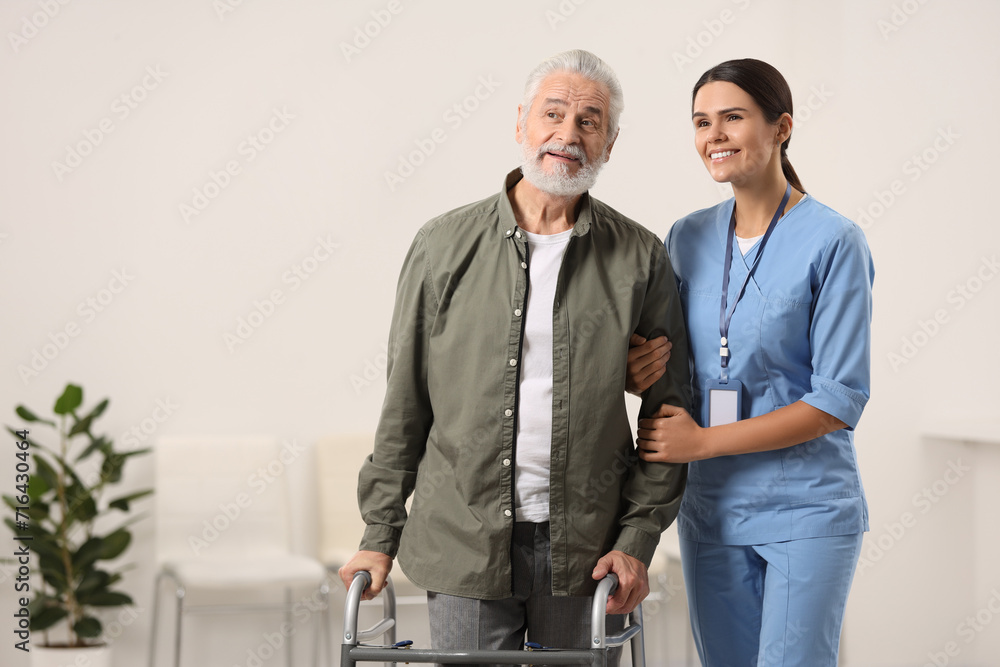 Smiling nurse supporting elderly patient in hospital, space for text Smiling nurse supporting elderly patient in hospital, space for text
