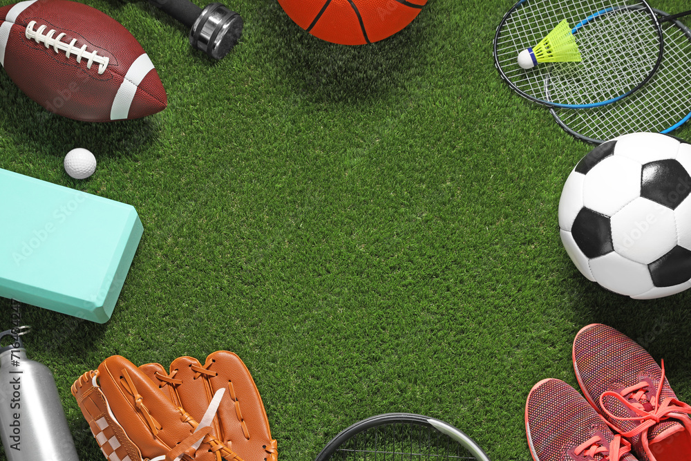 Frame made of different sports equipment on green grass, flat lay. Space for text