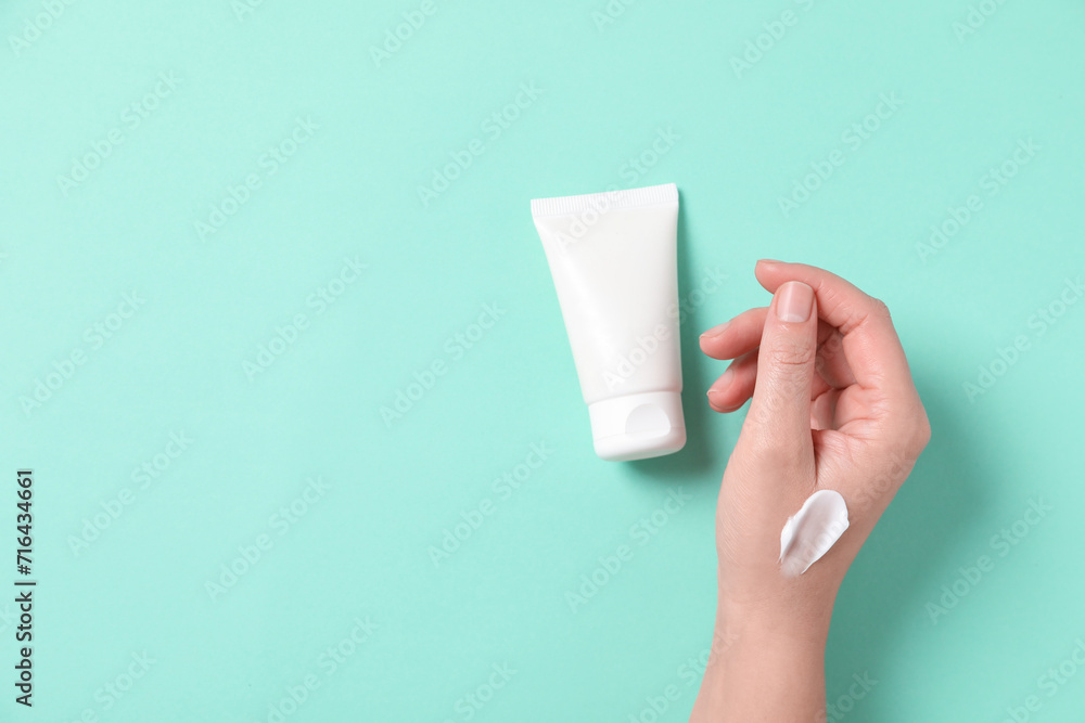 Woman with tube of hand cream on turquoise background, top view. Space for text Woman with tube of hand cream on turquoise background, top view. Space for text