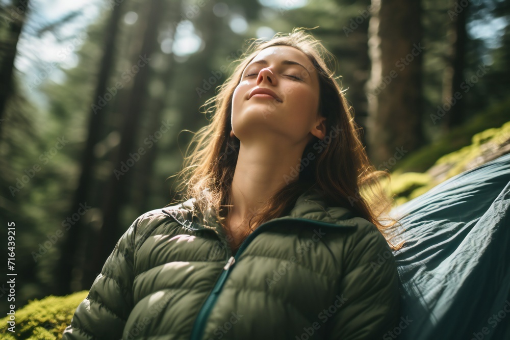 Young woman with eyes closed breathing fresh air while camping in woods Young woman with eyes closed breathing fresh air while camping in woods