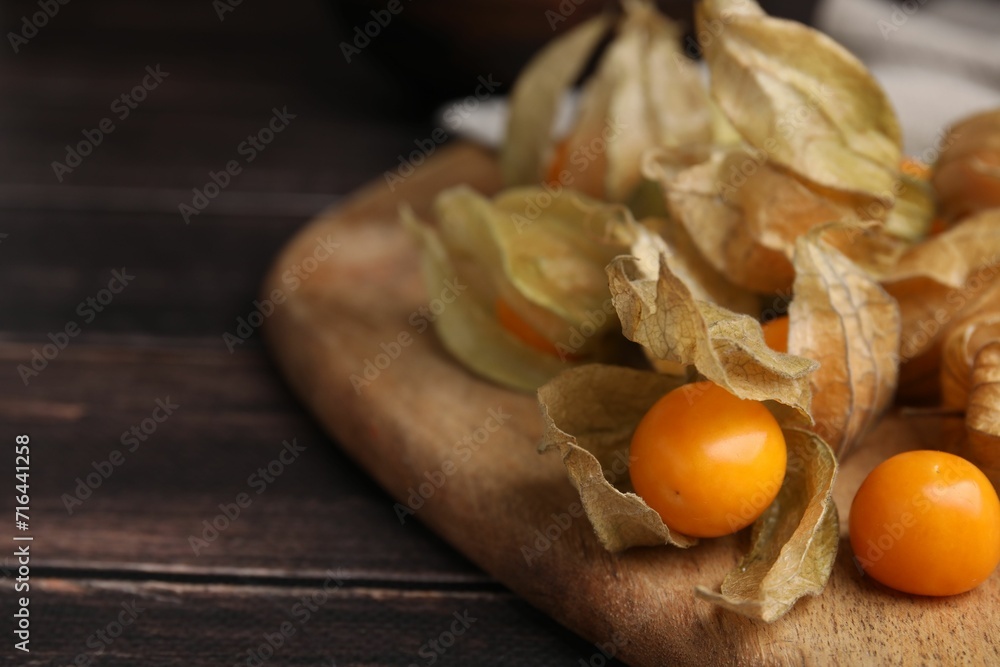 Ripe physalis fruits with calyxes on wooden table, closeup. Space for text